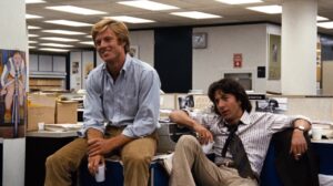 ATPM Robert Redford and Dustin Hoffman sitting at desks in a newsroom office.